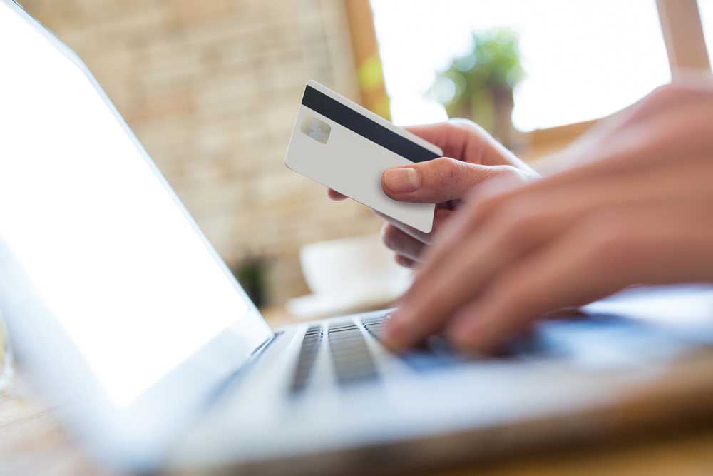 Persona che paga online con una carta davanti a un portatile
