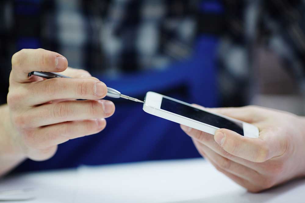 Tecnico che ripara uno smartphone con un cacciavite
