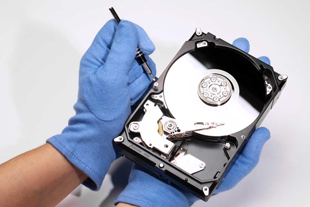 Hard disk aperto tenuto con guanti in laboratorio